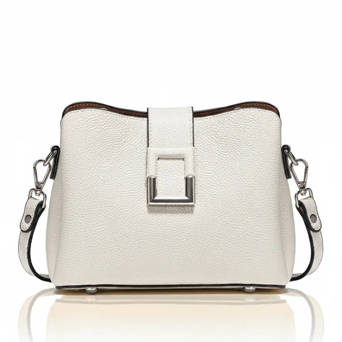 The main subject is a white handbag with a textured surface. It has a rectangular metal clasp in the center, a brown trim